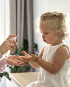 maman-pulverise-du-desinfectant-pour-les-mains-sur-les-mains-de-l-enfant-a-la-maison